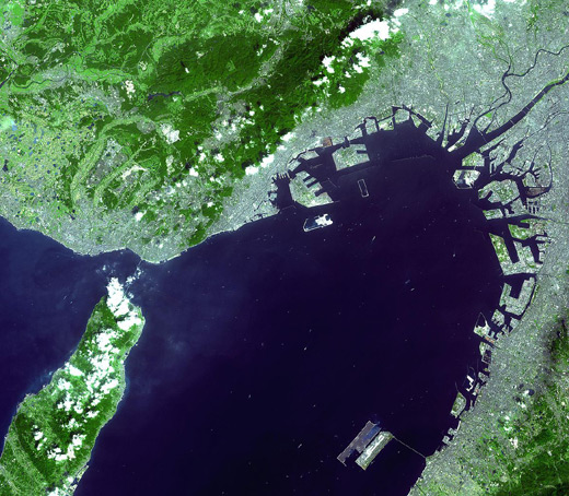
Satellite photo of Kansai Airport (lower-right island) in Osaka Bay. Kobe Airport is being built on the unfinished island near the middle of the photo. Central Osaka is in the upper-right corner, along with Osaka International.