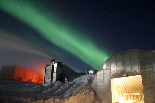 
A photo of the station in the night. The new station can be seen at the far left, the electric power plant is in the center, and the old vehicle mechanic's garage in the lower right. The green light in the sky is part of the aurora australis.