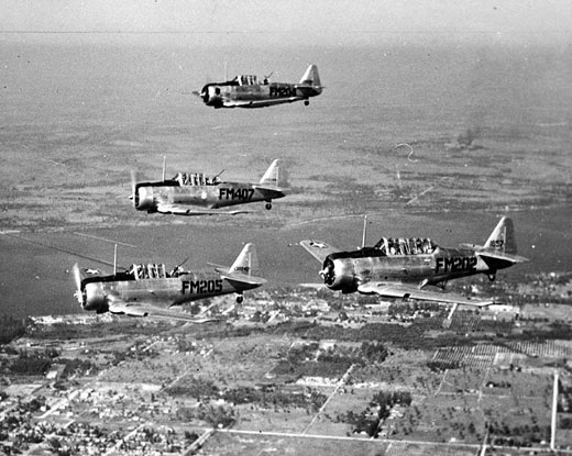 
A formation of four planes wing their way along the Caloosahatchee River above east Fort Myers to the Buckingham Flexible Gunnery School's range over the Gulf of Mexico (ca 1945). The plane on the right carries the tow target. The gunners shoot from the rear seat of the planes.