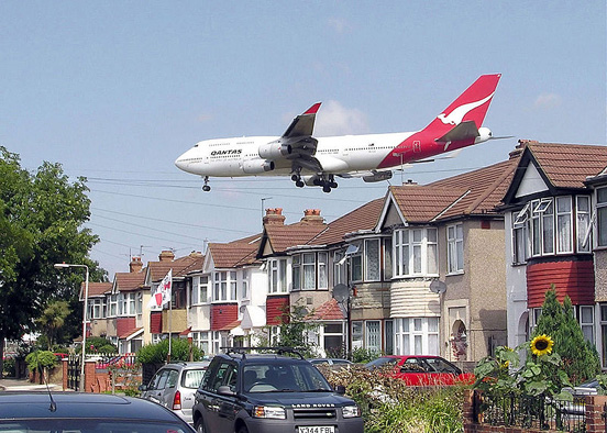 
A landing Qantas Boeing 747-400 passes close to houses on the boundary of London Heathrow Airport, England