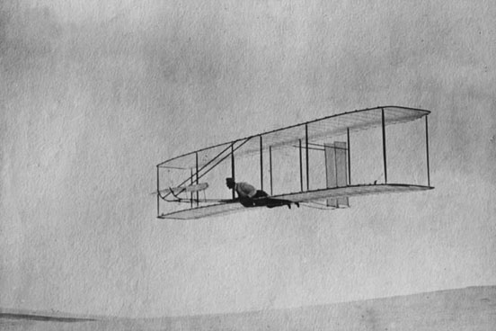 
The 1902 Wright Glider(Wilbur piloting) on one of its early test flights before replacement of the fixed double vertical rudder with a single steerable rudder.