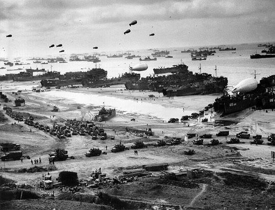 
Landing ships putting cargo ashore on one of the invasion beaches during the Battle of Normandy. Note the barrage balloons.