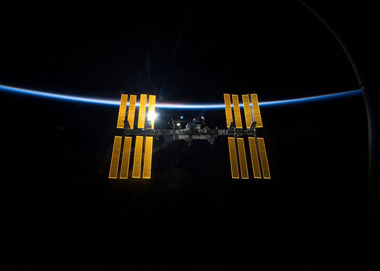 
The ISS against the blackness of space and the thin line of Earth's atmosphere, taken from the Space Shuttle Discovery as the two spacecraft begin their separation.