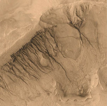 
This image taken by Mars Global Surveyor spans a region about 1,500 m (4,921 ft) across, showing gullies on the walls of Newton Basin in Sirenum Terra. Similar channels on Earth are formed by flowing water, but on Mars the temperature is normally too cold and the atmosphere too thin to sustain liquid water. Nevertheless, many scientists hypothesize that liquid groundwater can sometimes surface on Mars, erode gullies and channels, and pool at the bottom before freezing and evaporating.