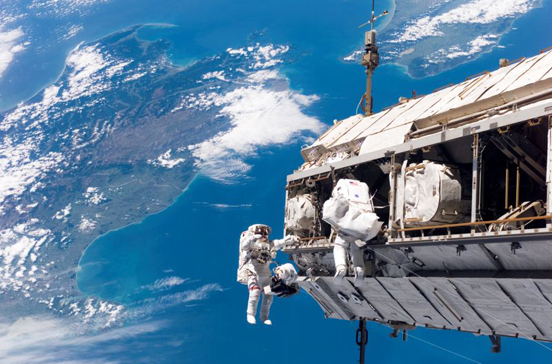 
Backdropped by a colorful Earth, astronaut Robert L. Curbeam, Jr. (left) and European Space Agency (ESA) astronaut Christer Fuglesang, both STS-116 mission specialists, participate in an EVA