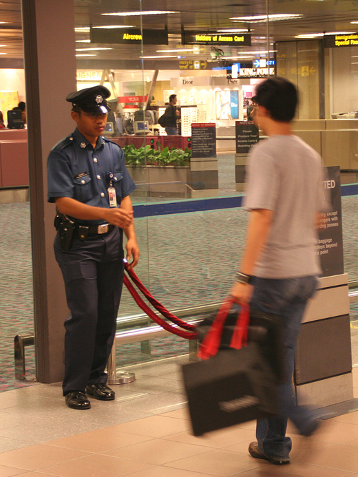 
An Aetos auxiliary police officer controlling access to the runway side of the Departure Hall at Terminal 1, Singapore Changi Airport. Such services are now provided by Certis CISCO.
