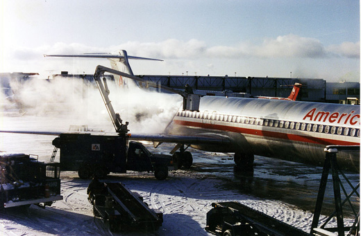
An American Airlines McDonnell Douglas MD-80 being deiced at Terminal B. In the background is a Northwest Airlines DC-9 parked at Terminal A.
