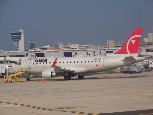 
Compass Airlines E175 parked in the east apron with the ground control tower and terminal D in the background.
