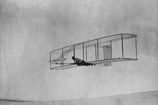 
The 1902 Wright Glider(Wilbur piloting) on one of its early test flights before replacement of the fixed double vertical rudder with a single steerable rudder.