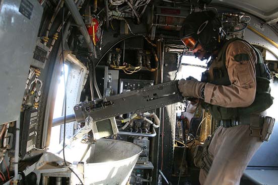
A door gunner manning a pintle-mounted .50-caliber machine gun aboard a USMC CH-46.